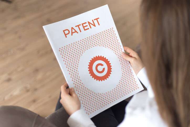 Eine Frau hält ein Patentdokument, das von einem Anwalt für Markenrecht aus Köln überprüft wurde